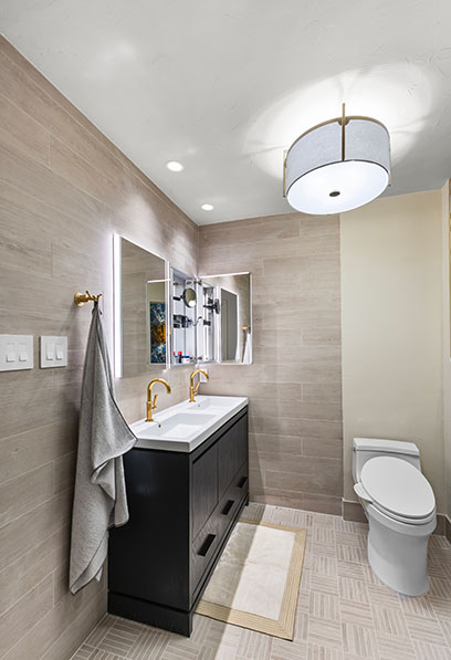 Elegant bathroom design with double vanity, gold fixtures, and soft lighting by Heather Toolin Designs in Austin, TX.