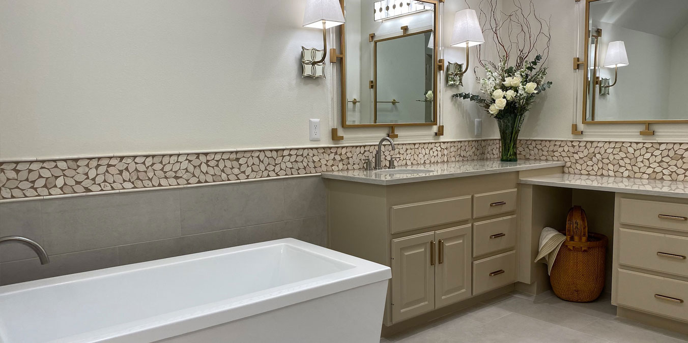 Elegant bathroom with freestanding tub, dual vanities, pebble wall accent, and floral decor for a spa-like feel.