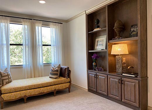 Cozy reading nook with built-in wooden bookshelves, yellow chaise lounge, and decorative pillows.