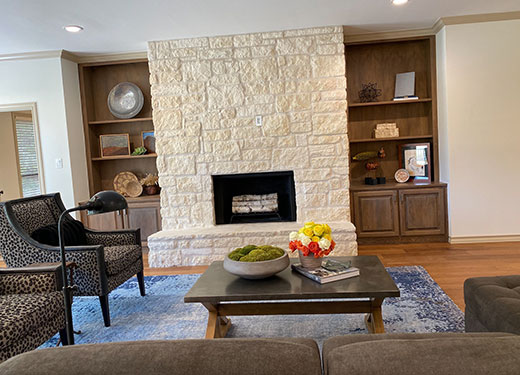 Cozy living room with stone fireplace and built-in wooden shelves.