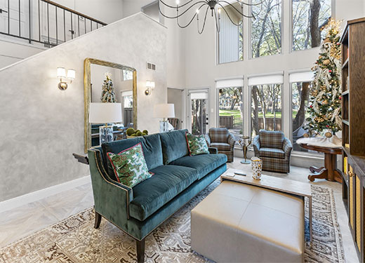 Modern living room with teal sofa, large wall mirror, and holiday decor.