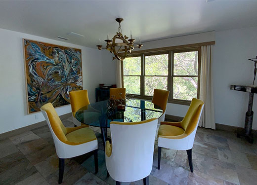 Elegant dining room with round wooden table, velvet chairs, and gold chandelier