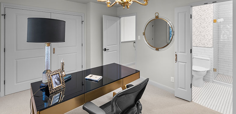 Sophisticated home office design with black and gold desk, round mirror, and elegant decor.