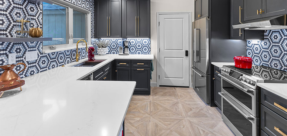 Modern kitchen with black cabinets, white countertops, and hexagonal backsplash tiles.