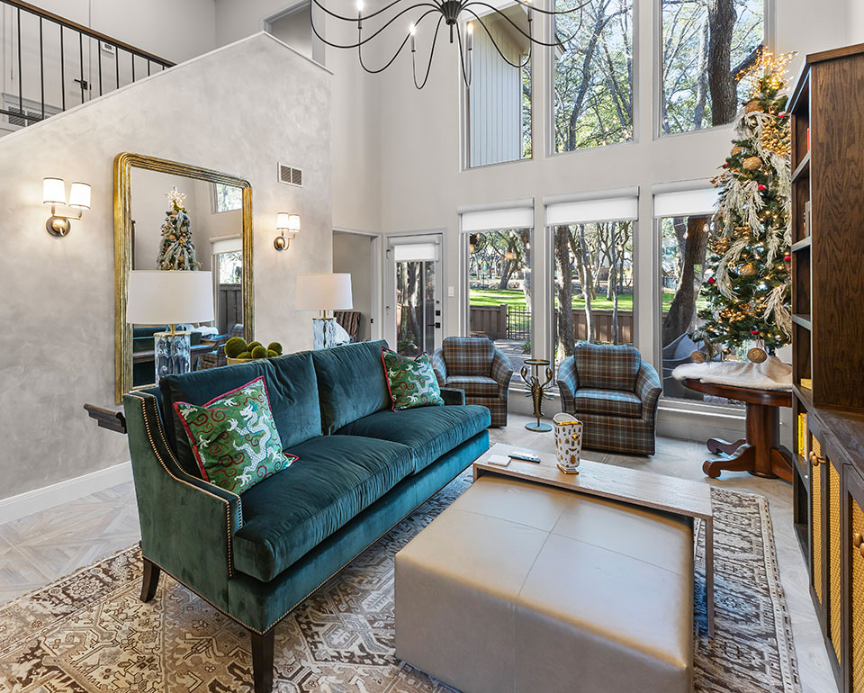 Stylish living room in Austin featuring a green velvet sofa, plaid armchairs, and large windows by Heather Toolin Designs.